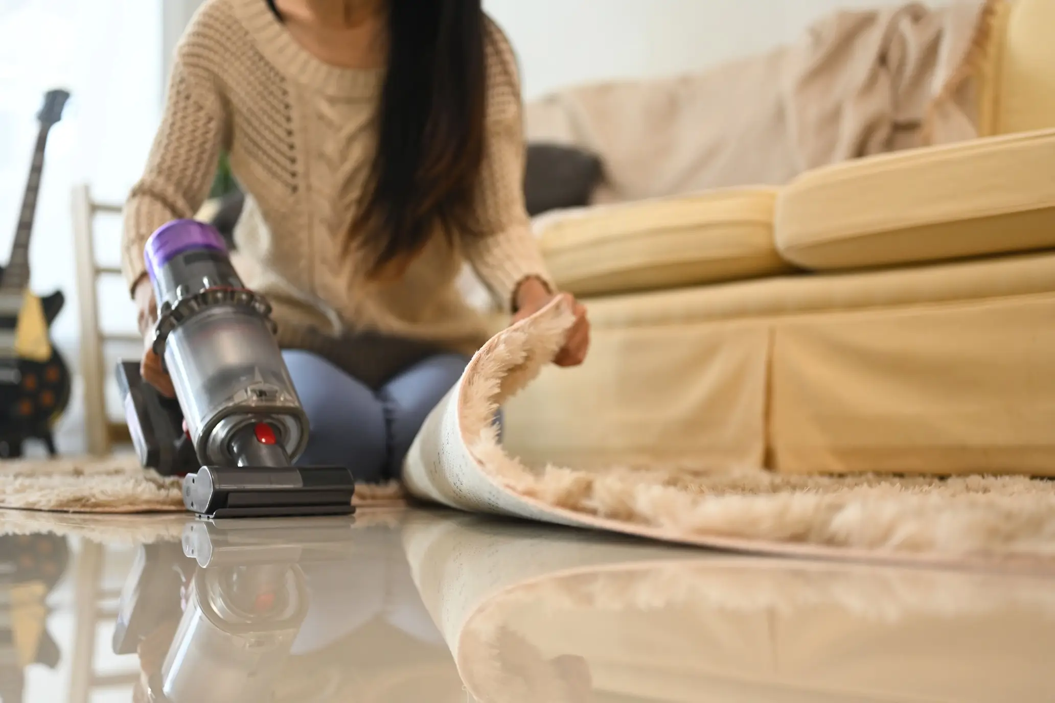 Lifting a rug to vacuum underneath during a deep clean in a Castle Rock home
