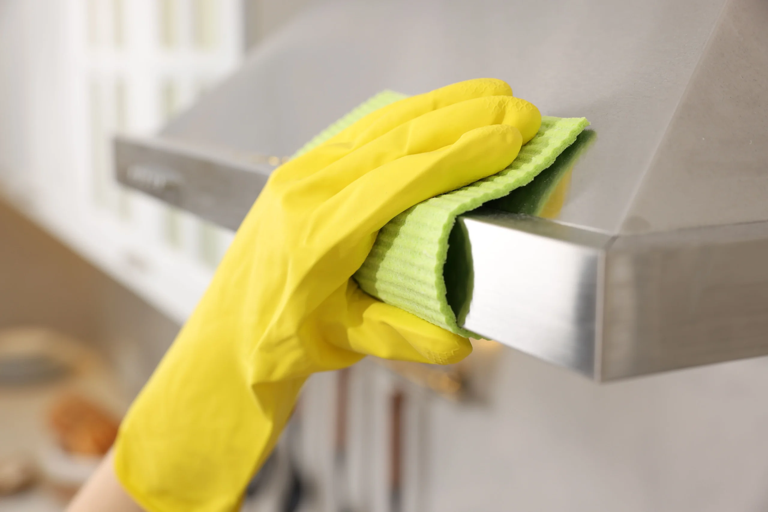 Gloved hands cleaning inside a kitchen hood during a move-in deep clean service in Castle Rock CO